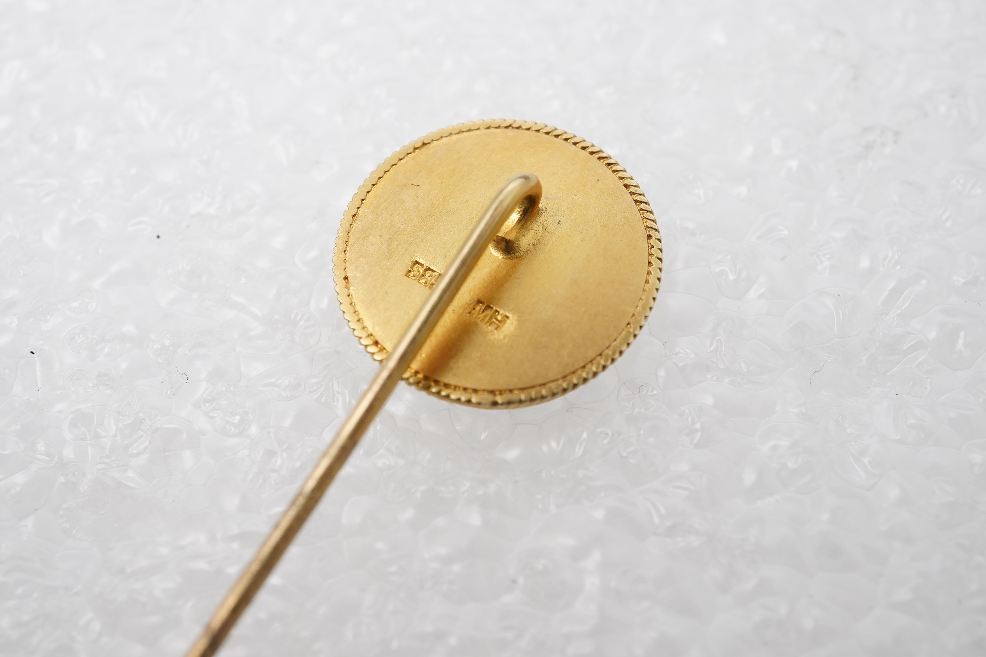 Two stick pins and a jadeite bar brooch, comprising: a bar brooch centring on an insect set with a pear-shape jadeite cabochon and a pearl, mounted in gold, length 7.5cm, stamped 14K, base metal pin; a stick pin capped w